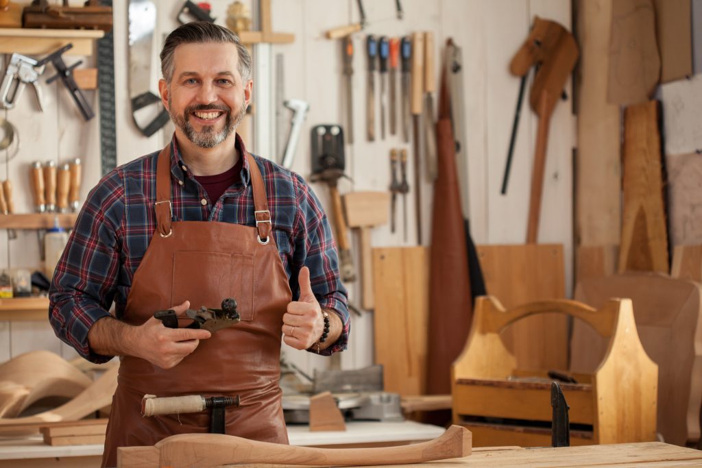 Happy Carpenter/Middle ages handsome carpenter finished creating cabriolet legs and smiles to the camera